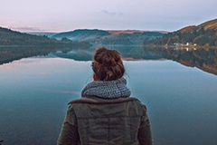 image of a lady contemplating a mountain lake