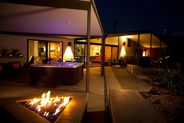 night scene of a couple relaxing in a beautifully designed back yard with a vacanza tarino hot tub